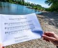 Bild: Armin Weigel
Ein Notenblatt mit dem Liedtext „Einst ging ich am Ufer der Donau entlang“ wird am Donauufer gehalten.
