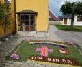 Bild: fjo
Auf dem Vorplatz der Pfarrkirche erinnert ein Blumenteppich an den Feiertag Fronleichnam.