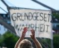 Bild: Andreas Arnold/dpa
Ein Demonstrant klatscht vor einem Plakat mit dem Slogan «Grundgesetz Wahrheit».