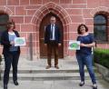 Bild: cog
Claudia Hammer, die Konrektorin der Pestalozzischule, (links) und Märchenerzählerin Tanja Weiß (rechts) präsentieren die ersten bunt ausgemaslten Bilder zum Märchen "Dort, wo der Drache wchläft". Bürgermeister Michael Göth (Mitte) dankt ihnen für ihr Engagement.