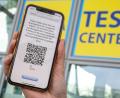 Bild: Peter Kneffel/dpa
Eine Frau hat sich mit ihrem Smartphone für einen Coronatest am Flughafen in München angemeldet.