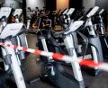 Bild: Hauke-Christian Dittrich/dpa
Ein rot-weißes Flatterband ist an Fahrradtrainern befestigt, die in einem Fitnessstudio stehen.