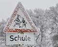 Bild: Peter Kneffel/dpa
Ein verschneites Verkehrsschild mit der Aufschrift „Schule“.