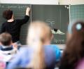 Symbolbild: Sebastian Gollnow/dpa
Eine Lehrerin schreibt in einer Schule an die Tafel.