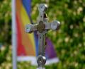 Bild: Henning Kaiser/dpa
Ein Kreuz steht bei einem Open-Air-Segnungsgottesdienst für Liebende vor einer Kirche. Im Hintergrund ist eine Regenbogenfahne zu sehen.
