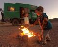 Bild: Familie Schmitt/exb
Die Wüste als großer Sandkasten für Romina und Levi (von links): Ein Lagerfeuer gibt es natürlich nur unter Aufsicht ihrer Eltern, Michaela und Thorben Schmitt. Im Hintergrund der alte Mercedes-Lkw der Familie, genannt „Frosch“, der aktuell in Dubai auf den nächsten Einsatz wartet.