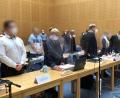 Archivbild: Ute Wessels/dpa
Die Angeklagten (1. Reihe 1.v.l., 2. Reihe 2.v.l. sowie 1. Reihe 4.v.l.) stehen im Gerichtssaal.