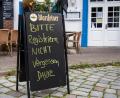 Bild: Daniel Bockwoldt/dpa
Eine Tafel mit der Aufschrift "Bitte Registrieren nicht vergessen. Danke" steht vor einem Restaurant.