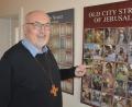 Bild: jr
Stadtpfarrer Anton Witt, hier neben einem Plakat mit Fotos der Jerusalemer Altstadt, freut sich auf seine achte Pilgerreise ins Heilige Land.