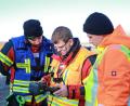 Bild: egl
Der Gruppenführer (blaue Weste, links) sieht zusammen mit dem Piloten (orange Weste, Mitte) und dem Ausbilder (rechts) auf die Fernbedienung; dort wird ebenfalls das Bild der Drohne übertragen.