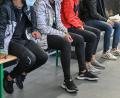 Symbolbild: Patrick Pleul
Migranten sitzen bei der Bundespolizei auf Bierbänken und warten.