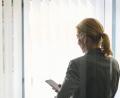 Bild: Annette Riedl/dpa
Eine Frau steht in einem Bürozimmer und hält ein Smartphone in der Hand (gestellte Szene).