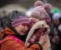 Bild: Visar Kryeziu/AP/dpa
Eine weinende Frau mit einem Kind im Arm  am Grenzübergang im polnischen Medyka.