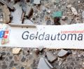 Symbolbild: Patrick Pleul
Splitter und ein Schild mit der Aufschrift "Geldautomat" liegen auf dem Fußboden vor einem gesprengten Geldautomaten.