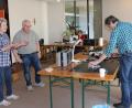 Bild: ds
Während Max Sturzer (rechts) sich dem defekten Radio-Recorder widmete, erledigte Ulrike Loos an der Nähmaschine Ausbesserungsarbeiten. Winfried Franz (Zweiter von links) regelte den geordneten Ablauf.