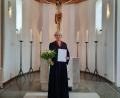 Bild: Evang. Pfarramt Tirschenreuth/exb
Anna Merzinger mit Blumen und Ernennungsurkunde vor dem Altar der Erlöserkirche in Tirschenreuth.