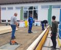 Bild: gi
Die Sanierung des Flachdaches des Aula-Gebäudes der Grundschule Moosbach ist voll im Gange; hier die Zimmerei-Firma im Gespräch mit Hausmeister Wolfgang Piehler (links).