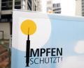 Bild: Bernd Weißbrod/dpa/Symbolbild
Blick auf ein Plakat mit der Aufschrift „Impfen schützt“ vor einem Impfzentrum.