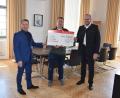 Bild: Veronika Rumpler/exb
Landrat Andreas Meier (rechts) und Sparkassendirektor Gerhard Hösl (links) übergeben den Spendenscheck über 3000 Euro an Mario Schieder von der SpVgg Windischeschenbach.