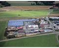 Luftbild: akp
Der Stadtratsbeschluss (Ratsbegehren) sieht die Erweiterung des Industriegebietes West, in Verbindung mit einer Freiflächen-Photovoltaikanlage bis zur Teunzer Straße (oben) vor. Da ein breiter Grüngürtel als Abstand zur Ortschaft Hof (rechts) in die Planung einfloss, würde eine weitere PV-Anlage über der Straße (Feld links oben) entstehen. Die BI „Hof plus“ will die PV-Anlagen mit dem Bürgerbegehren verhindern.