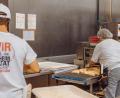 Bild: sfo
In der Backstube der Bäckerei Kutzer in Konnersreuth läuft vieles automatisch. Die Backwaren laufen auf einem Förderband durch eine Vorrichtung, in der sie mit einer Laugenschicht glasiert werden. Ein Mitarbeiter bestreut sie danach mit Sesam.