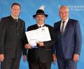 Bild: Bayerisches Staatsminister des Inneren, für Sport und Integration
Anton Hirnet (Mitte) freut sich über die von Staatsminister Joachim Herrmann (rechts) und Christian Kühn verliehene Ehrenmedaille.
