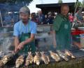 Bild: dob
Die gegrillten Forellen frisch vom Rost schmecken. Emmerich Sterbling (links) brutzelt die Fische im Akkord.