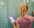 Bild: Julian Stratenschulte
Eine Lehrerin schreibt an eine Schultafel und hält dabei einen Tablet-Computer in der Hand. In Amberg wurden die Weichen gestellt, dass alle Erstklässler mit einem iPad ausgestattet werden können.
