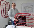 Bild: bl
Norbert Schindler demonstriert am Teunzer Firmenstandort, wie die roten Kunststoffschlangen verbaut werden, durch die später Wasser strömen und den umgebenden Beton aufwärmen soll.