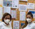 Bild: Alexandra Scherer
Sie helfen und informieren. Ärztin Marina Koller (links) und die medizinische Fachangestellte Michelle Pamler vor einer Wand mit Hinweisen und Terminen.