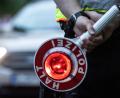 Bild: Paul Zinken/dpa/ZB/Symbolbild
Ein Polizist hält bei einer Verkehrskontrolle eine Winkerkelle in der Hand.