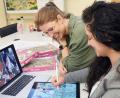 Bild: Gabi Schönberger
So geht das also. "PuzzleYou"-Projektleiterin Nina Lenfers lässt sich von Illustratorin Stefania Santoro (rechts) erklären, wie die Idee zu einer Weidener Straßenszene zum Teil eines Wimmelbilds wird.