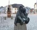 Bild: lnz
In zentraler Lage am Unteren Markt in Mitterteich sitzt eine Hankerl-Skulptur auf einem Granitsockel – der Hankerlbrunnen erinnert an die Sage von den Hankerln. Unweit davon steht der größere Schmiedbrunnen (hinten links).