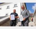 Bild: Stadt Tirschenreuth/exb
Projektleiter Falk Leopold von Brückner & Brückner Architekten (links) und Bürgermeister Franz Stahl (rechts) mit der Auszeichnungsplakette und Urkunde vor dem neuen Lernstandort.
