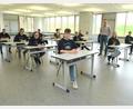 Bild: Stiftland-Gymnasium/exb
Das Foto zeigt einige Abiturientinnen und Abiturienten im Prüfungsraum mit ihrem Oberstufenkoordinator Michael Beugler.
