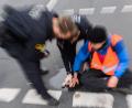 Bild: Julian Stratenschulte/dpa
Polizisten versuchen festgeklebte Hände von Aktivisten von der Straße abzulösen.