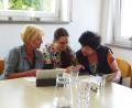Bild: Kathleen Busse, Malteser/exb 
Eine ehrenamtliche Helferin (Mitte) erklärt zwei Teilnehmern den Umgang mit Handy und Tablet.