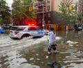 Bild: Jake Offenhartz/AP/dpa
Hochwasser auf den Straßen von New York: Im Stadtteil Brooklyn versucht ein Mann, mit einem Stock einen Abfluss zu reinigen, während ein Polizeiwagen vorbeifährt.