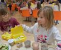 Bild: ubb
Albina und Pia (von links) schlichten ihre neuen Biobrotzeitboxen mit Biolebensmitteln aus der Region voll. Die beiden Mädchen mögen fast alles, was auf dem Frühstückstisch für Grundschulkinder vorbereitet wurde und greifen zu.
