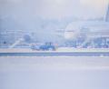Bild: Jason Tschepljakow/dpa
Ein Schneeräumer fährt im Schneetreiben auf dem Flughafen vor einer Maschine entlang.