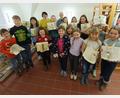 Bild: wku
Stolz zeigen die Kinder die Ergebnisse des Buchfalt-Workshops. Hinten Büchereileiterin Maria Klobes-Martin (rechts) und die Expertin Christine Simmel (links).