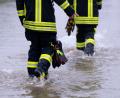 Bild: Sven Hoppe/dpa
Feuerwehrleute gehen über eine überflutet Straße.