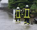 Bild: Sven Hoppe/dpa
Feuerwehrleute gehen über eine überflutet Straße in Dasing.