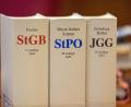 Symbolbild: Thomas Banneyer
Das Strafgesetzbuch (StGB), die Strafprozessordnung (StPO) und das Jugendgesetzbuch (JGG) stehen auf einem Richtertisch.