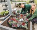 Bild: Portner
Anna-Maria Benz (links) und Sophie Pösl pflanzen die Mustergräber in der Gärtnerei Baumer an.