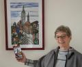 Bild: Martina Heberl/exb
Bärbel Eichenmüller vom Weltladen-Team mit der neuen Auerbach-Schokolade vor dem Bild, das Sr. Liselotte Schuhmann gemalt und als Motiv für die Tafel zur Verfügung gestellt hat.