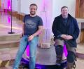 Bild: Tobias Wagner/exb
Pfarrer Markus Meier (rechts), Holzbildhauer Marco Bruckner und das dreiteilige Kunstwerk "Einfach da sein", auf dem man auch sitzen kann, wie zu sehen ist.