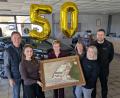 Bild: pz
Seniorchefin Gabriele Braunschläger (Mitte) mit ihren Familienangehörigen und den ersten Mitarbeitenden – von links Thomas Lochner (einst erster Lehrling in der Werkstatt) und Antonia sowie (von rechts) Geschäftsführer Hubert Beinrucker, seine Frau Iris und Karin Bartl, einst erste Auszubildende im Büro. Das Bild im Vordergrund zeigt den damaligen Werkstatt-Neubau an der Konnersreuther Straße, errichtet kurz nach der Gründung der Firma vor 50 Jahren. Jasmin Gmeiner (Tochter von Gabriele Braunschläger) war zum Fototermin verhindert.