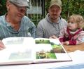 Bild: Uwe Ibl
Der Störnsteiner Schnapsbrenner Wolfgang Kriechenbauer schaut sich mit Sohn Hannes und Enkelin Neele im Fotoalbum die Bilder von der Pflanzaktion für die neue Streuobstwiese an.