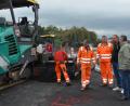 Bild: dob
Eine große Asphaltiermaschine trägt den Deckenbau auf den Amselweg auf. Die Arbeiten haben sich wegen wettertechnischen Gründen verzögert, informierte Außendienstleiter Michael Gösl (Zweiter von rechts), der sich mit Bürgermeister Andreas Wutzlhofer (rechts) und den städtischen Mitarbeitern Jörg Fikus und Manfred Bojer (von links) vom Fortschritt überzeugten.